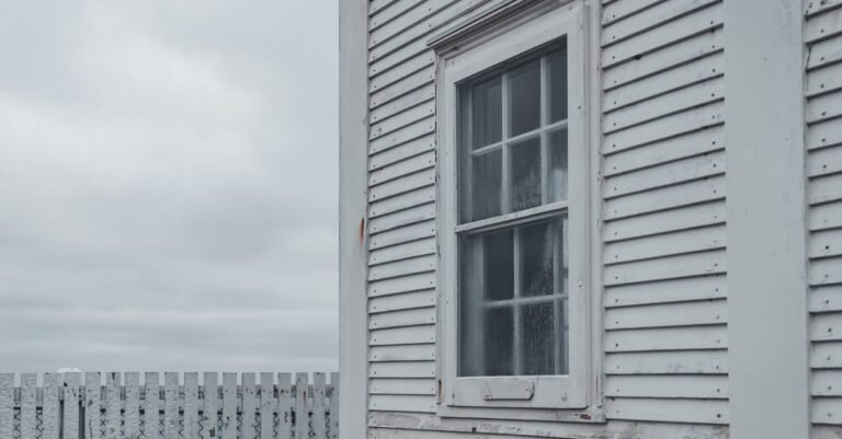 Weathered white wooden siding on a house wall under a flat overcast sky