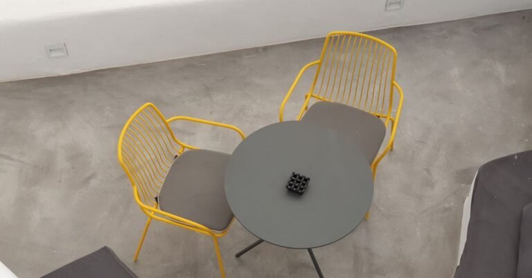 Overhead view of a plain concrete patio slab with two yellow chairs and a small round table