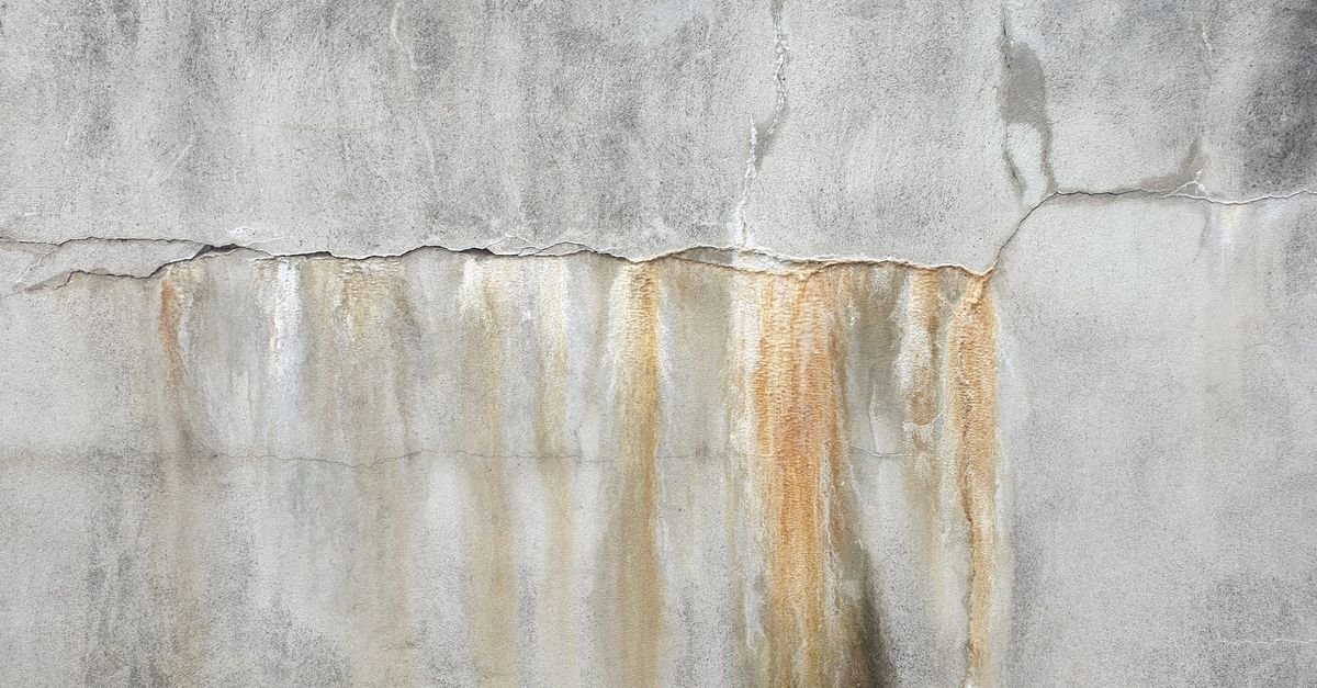 Weathered concrete surface showing surface cracking and patchy dark staining