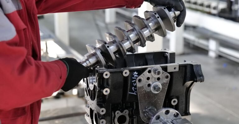 Mechanic fitting a crankshaft into an engine block on a workshop bench