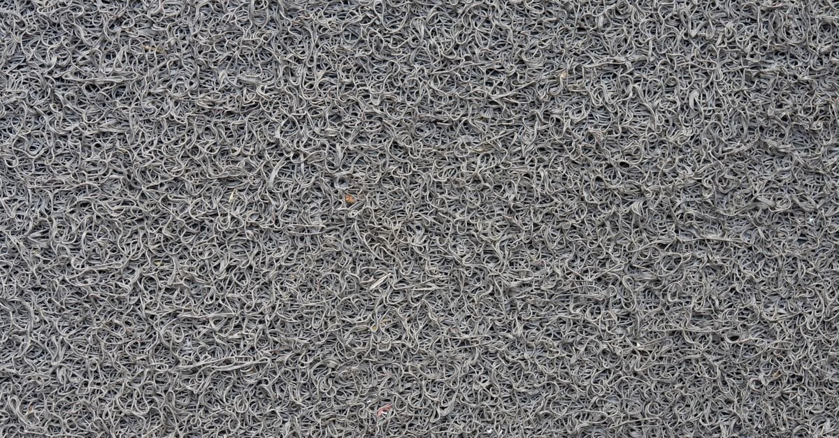 Close-up of a grey synthetic mat showing tight looped pile and its backing