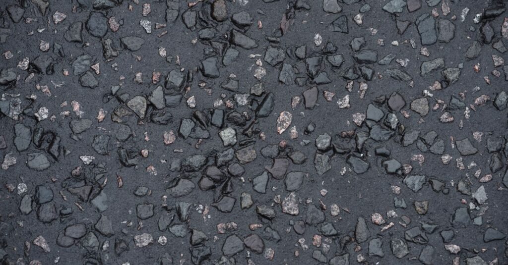 Wet asphalt driveway surface showing the aggregate and binder up close