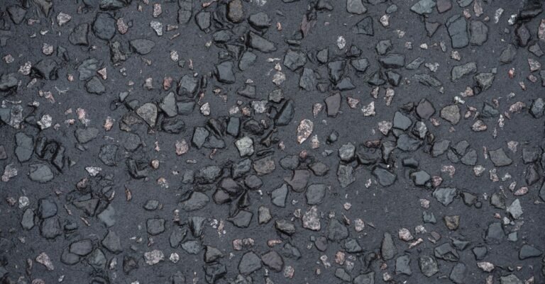 Wet asphalt driveway surface showing the aggregate and binder up close