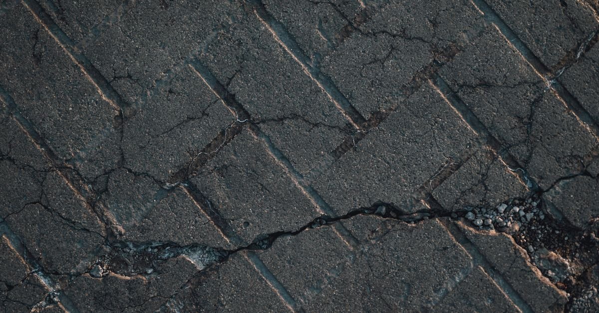 Cracked, raveling asphalt driveway losing aggregate at the surface