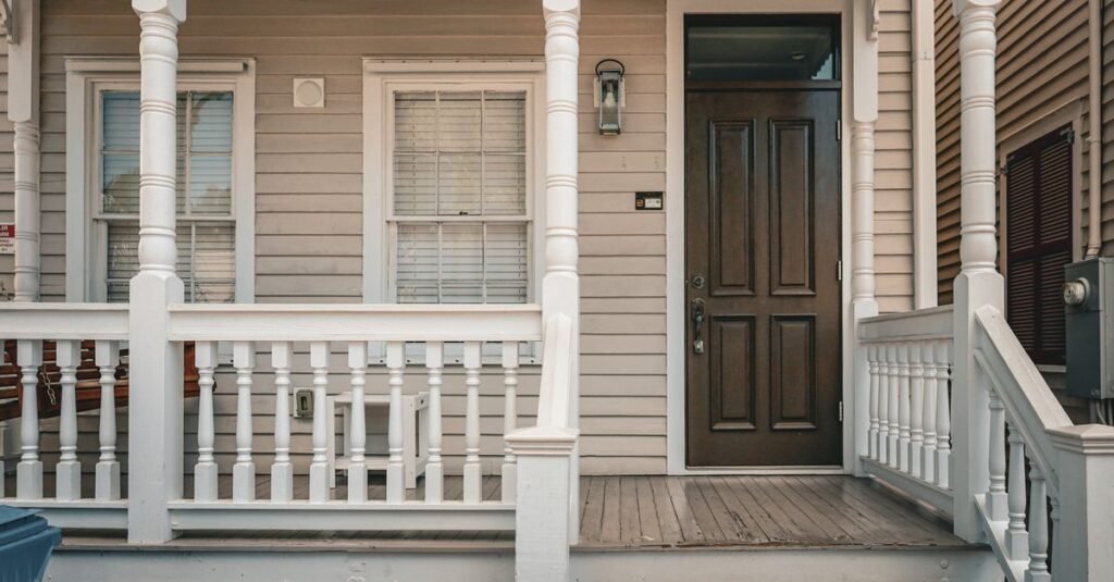 Classic painted wood porch with white siding, railings and a picket fence