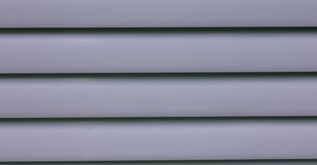 Close-up of overlapping gray vinyl siding panels showing the lap profile