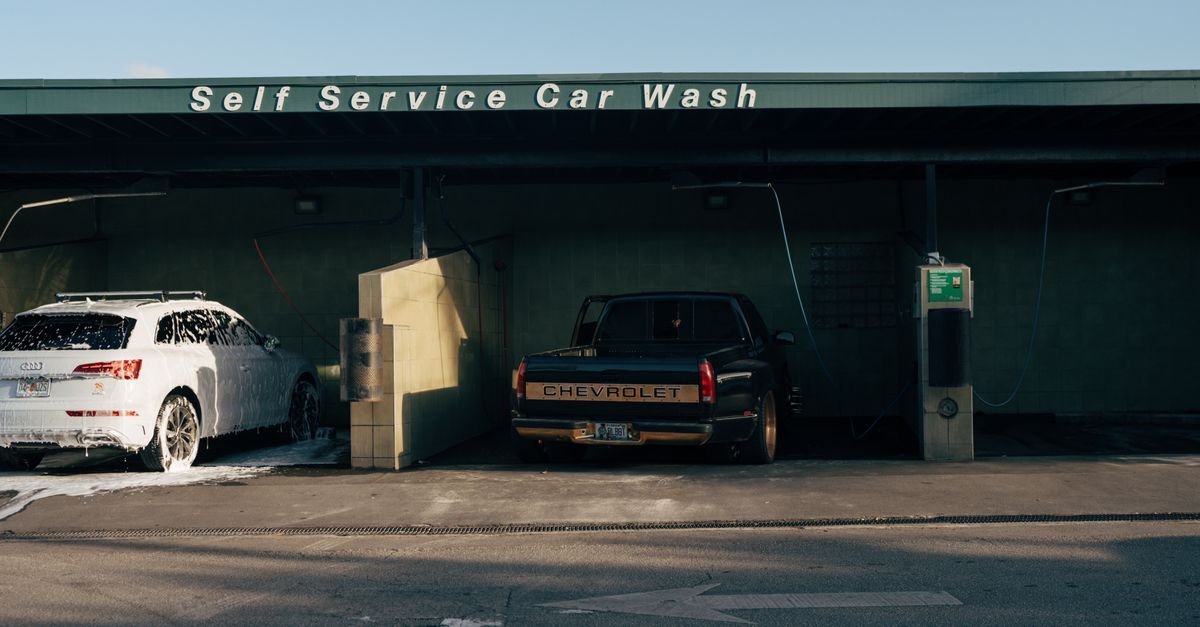 Self service car wash featuring a foam-covered Audi and a Chevrolet truck