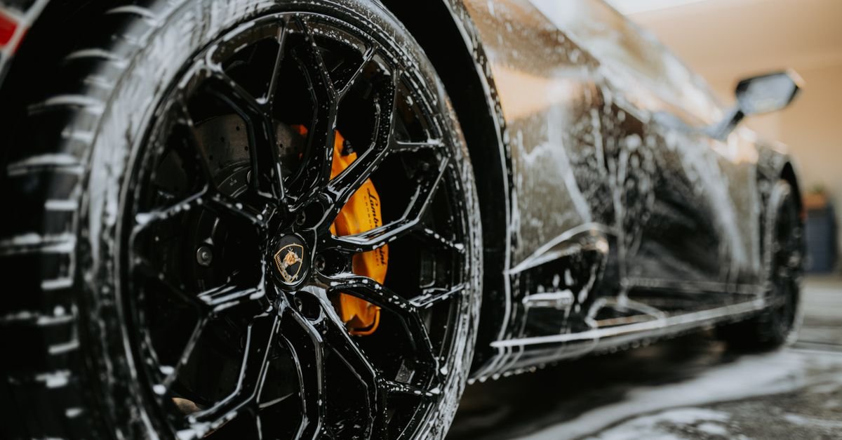 Alloy wheel covered in soap suds during a detailed car wash