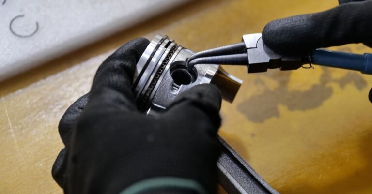 Gloved hands working on a plunger rod at a workshop bench during a pump rebuild