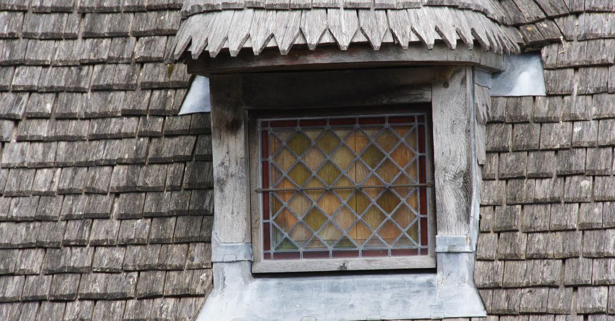 Dormer window framed by weathered wood shingles showing the butt edge of each course