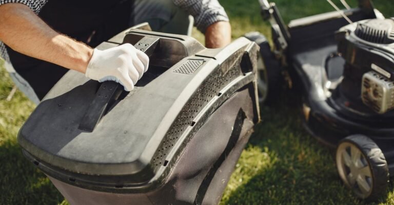 Man lifting the grass bag off a walk-behind lawn mower in a sunny back garden