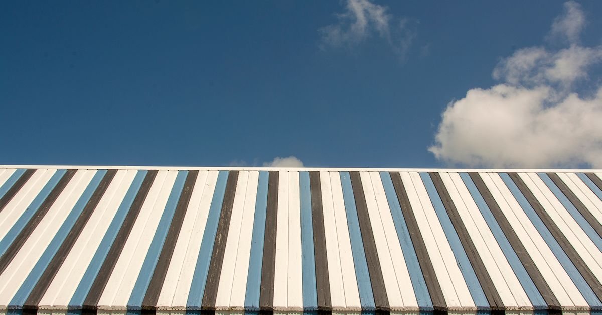 Ribbed metal roof panels running from ridge to eave, the down-slope direction a rinse should follow