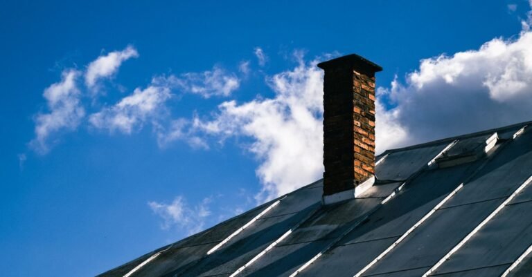 Standing seam metal roof panels running down to the eaves beside a brick chimney