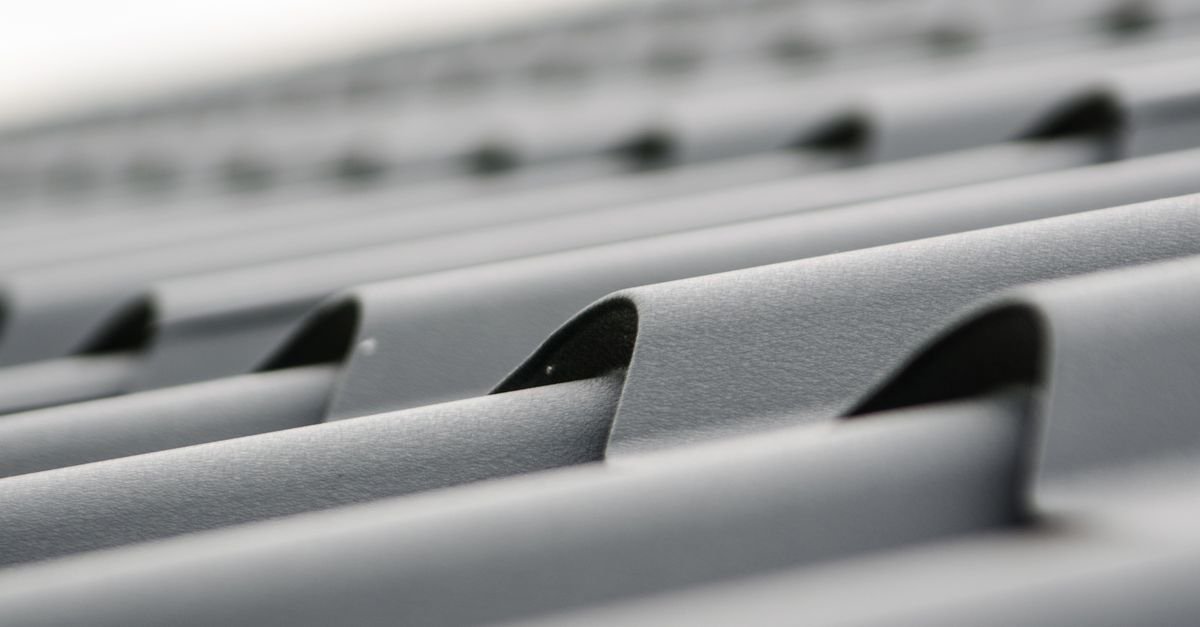 Close-up of grey painted metal roof sheets, the thin factory coating that cleaning has to protect