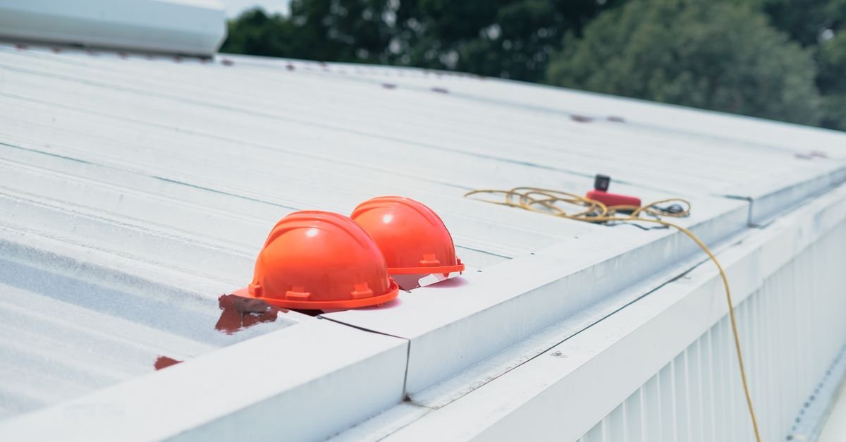 Hard hats and fall protection equipment laid out on a metal roof before work starts