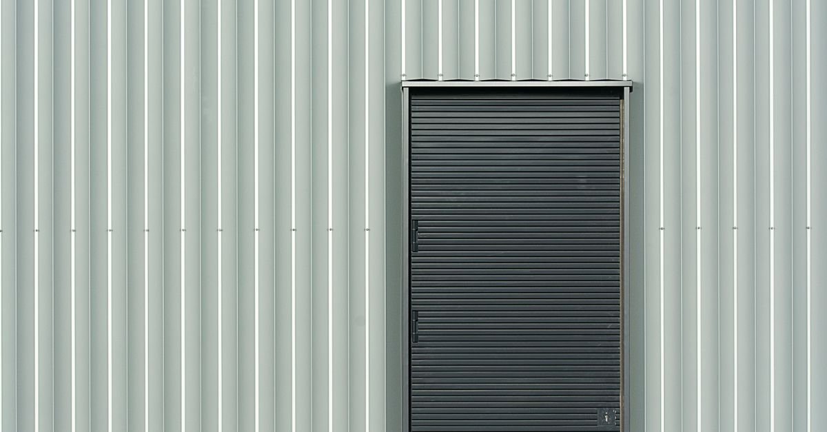Sleek grey aluminium siding panels running alongside a black metal door on a modern building