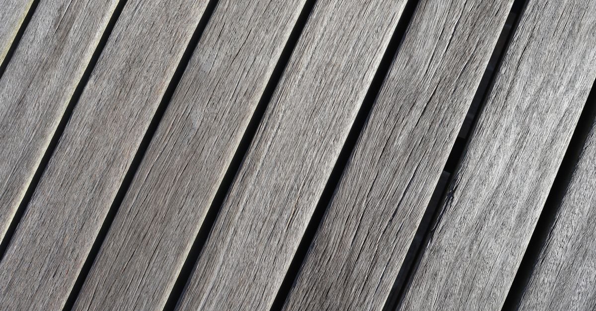 Weathered grey deck planks with open silvered grain, the surface FPL describes as severely sunburned