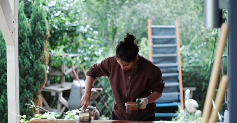 Applying a protective wood finish outdoors with a brush, the step that only works once the boards underneath are dry