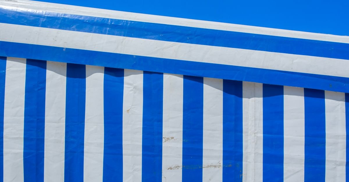 Close-up of blue and white striped canvas with vivid colours under a clear blue sky