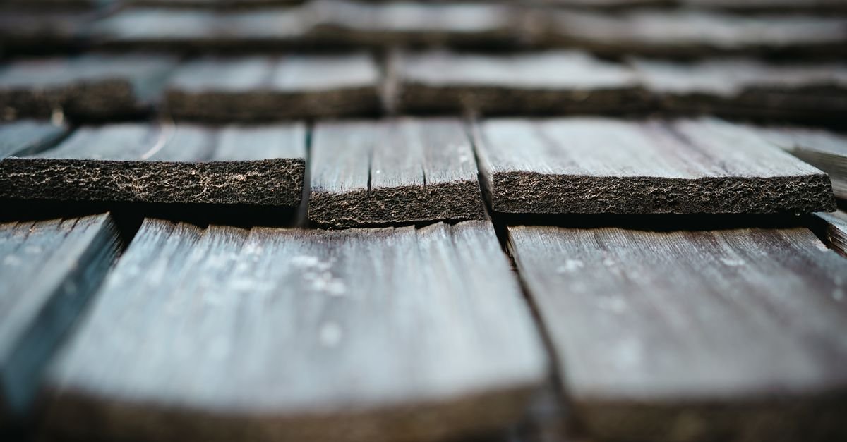 Weathered cedar shingles with dark aging and streaking across the grain