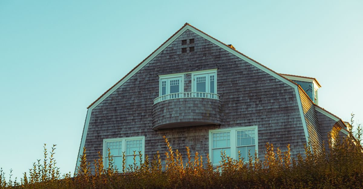 Two-storey cedar-shingled house with an upper balcony that a wand has to reach