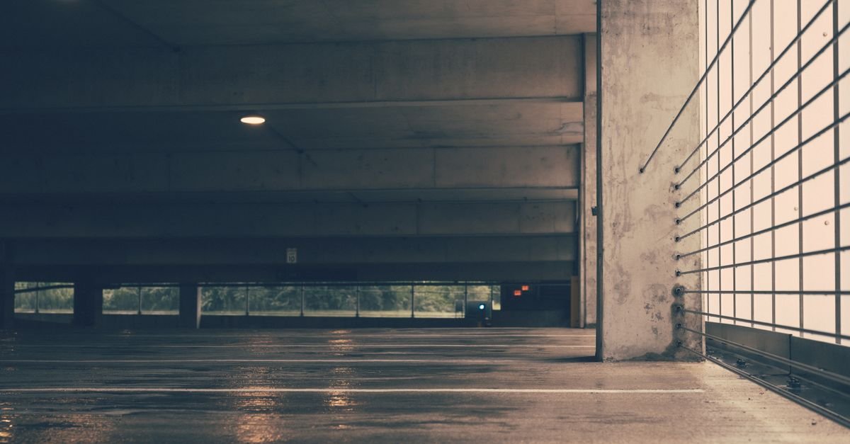 Indoor concrete floor with standing water spreading across it under overhead lighting