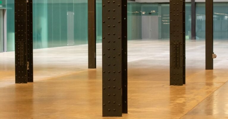Wide industrial room with steel pillars and a reflective polished concrete floor