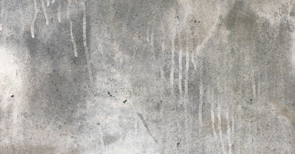 Weathered concrete surface showing pale vertical streaks where minerals have leached out