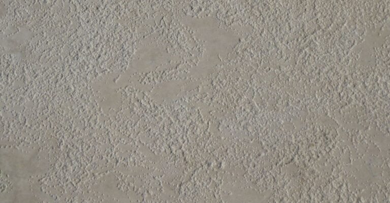 Close-up of a bare beige concrete slab showing open surface pores and fine aggregate
