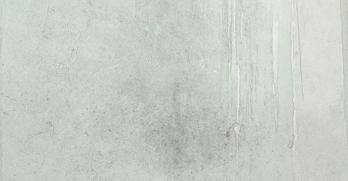 Concrete surface marked with dark patchy staining and colour variation