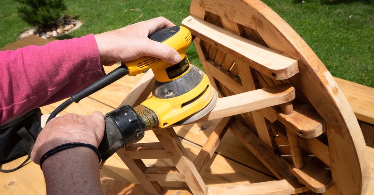Person running a power sander across outdoor timber boards, the only real fix once a deck has furred