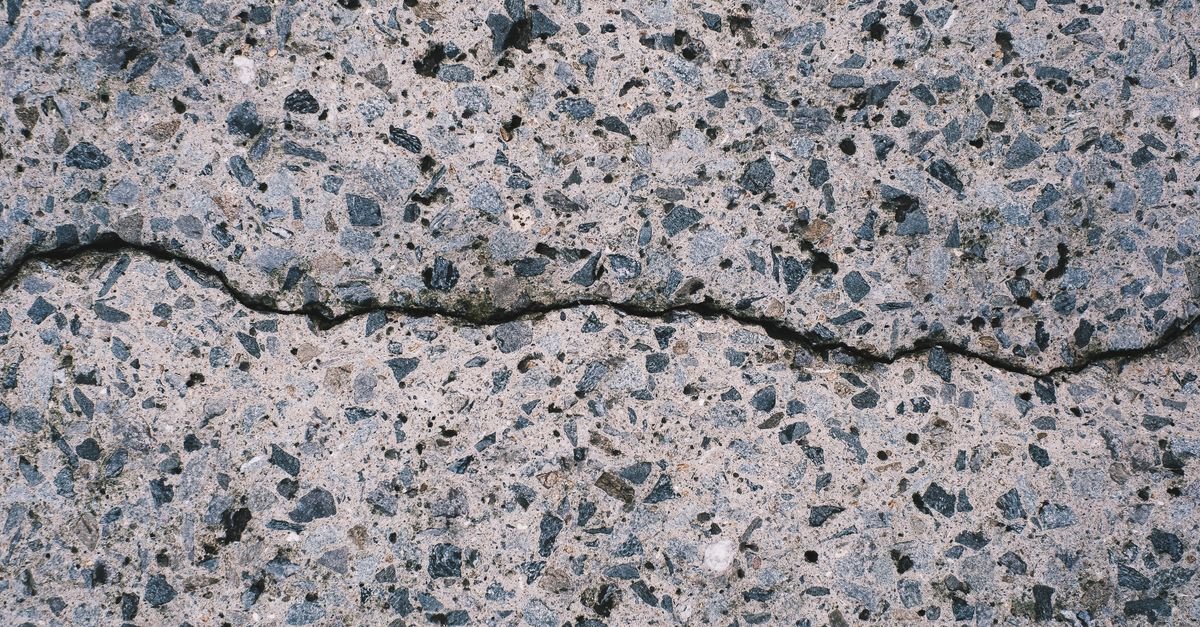 Close-up of a rough, open-textured concrete surface showing exposed aggregate
