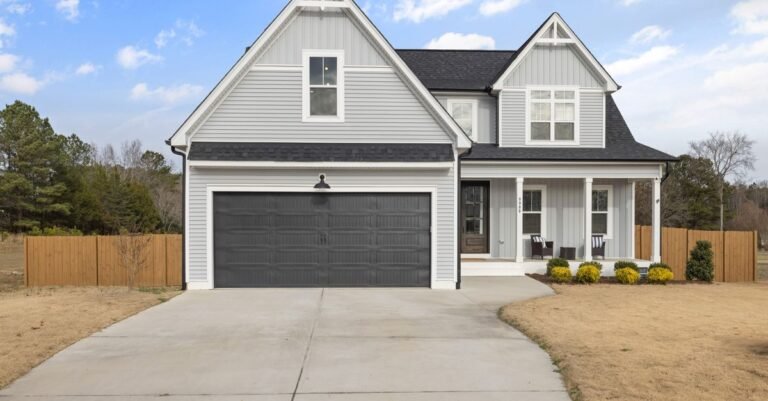 Two-storey suburban house with a wide concrete driveway sloping down from the garage