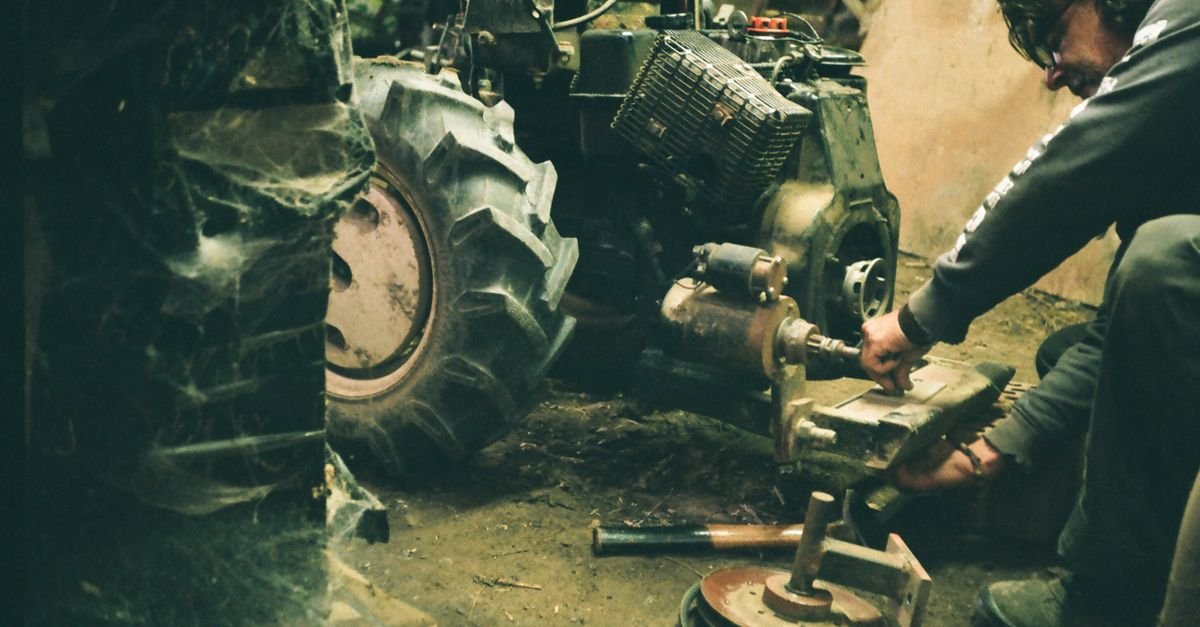Mechanic leaning into the engine compartment of a tractor in a workshop