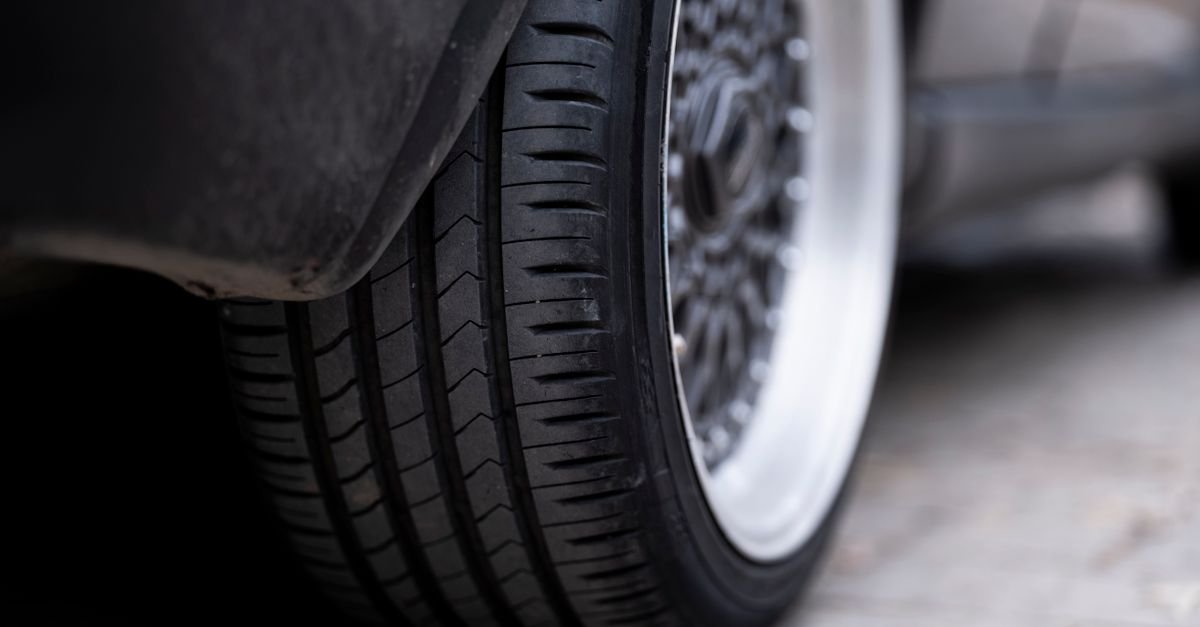 Close-up of a car tyre resting on a hard grey surface, showing tread and sidewall contact
