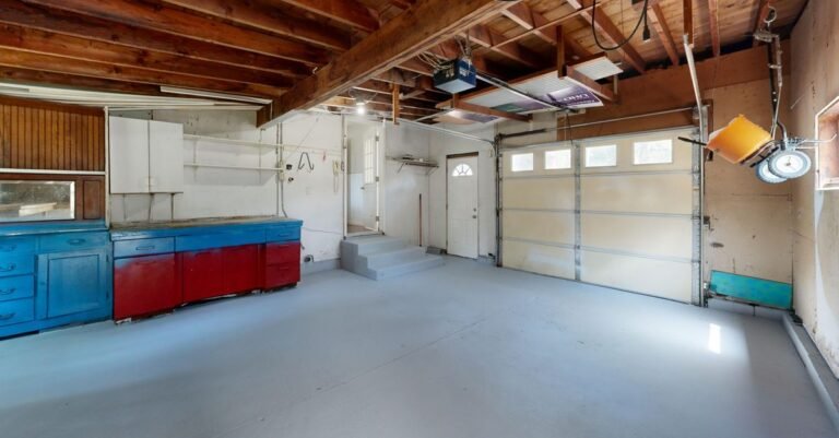 Empty home garage with a bare concrete floor and storage cabinets along one wall