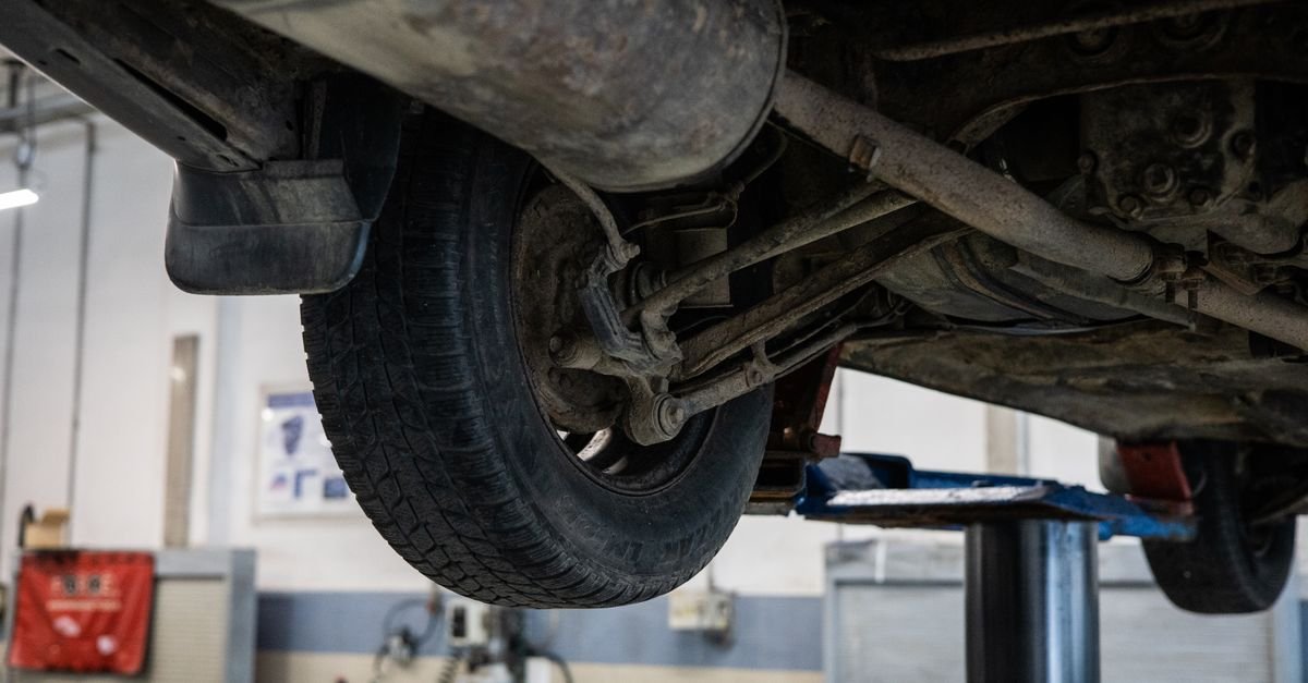View up into a car undercarriage on a workshop lift, where weeping seals start a drip