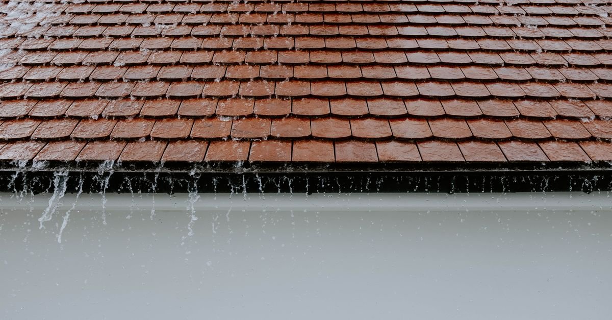 Rainwater cascading off the tiled edge of a roof at the eaves