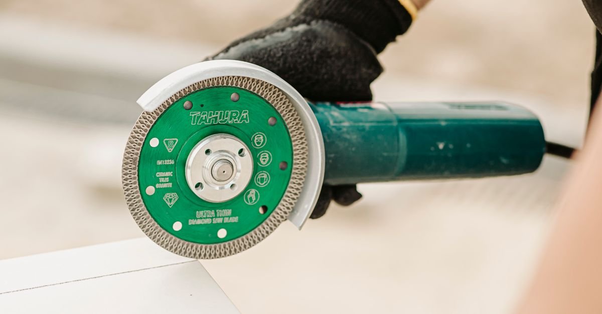 Worker running an angle grinder fitted with a diamond blade during a renovation, the tool that takes a painted floor back to bare concrete