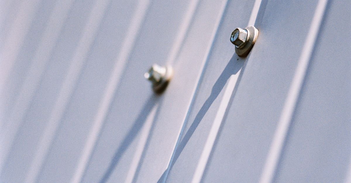 Metal screws securing a steel sheet, each one a penetration through the factory coating