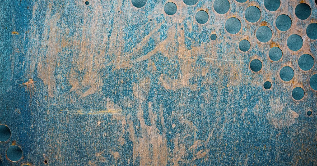 Old blue painted metal with scratches and small holes, the two ways a coating gets opened