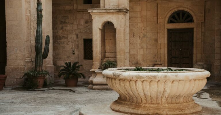 Weathered cream limestone courtyard paving and a carved stone fountain basin stained by standing water