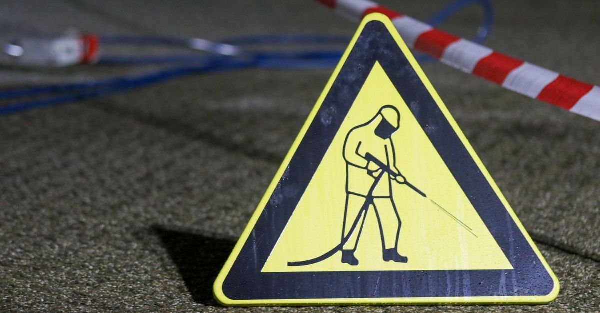 Pressure-washing warning sign and barrier tape marking a commercial cleaning work area