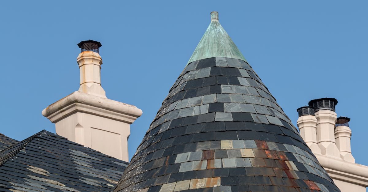 Copper-topped chimney flashing sitting above a tiled roof slope, a source of metal runoff onto the tiles below