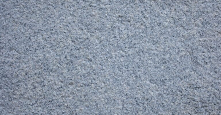 Close-up of a rough grey concrete pavement surface showing its open porous texture