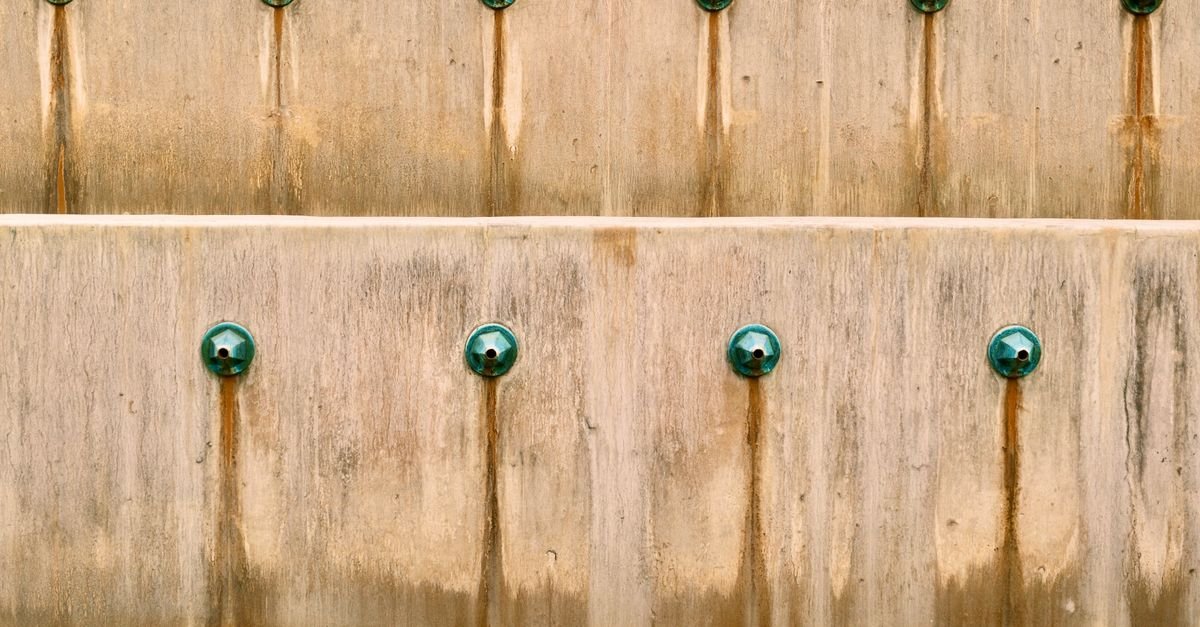 Rust-coloured staining running down a weathered concrete wall