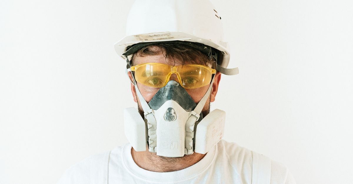 Worker wearing sealed safety goggles and a respirator before handling cleaning chemicals