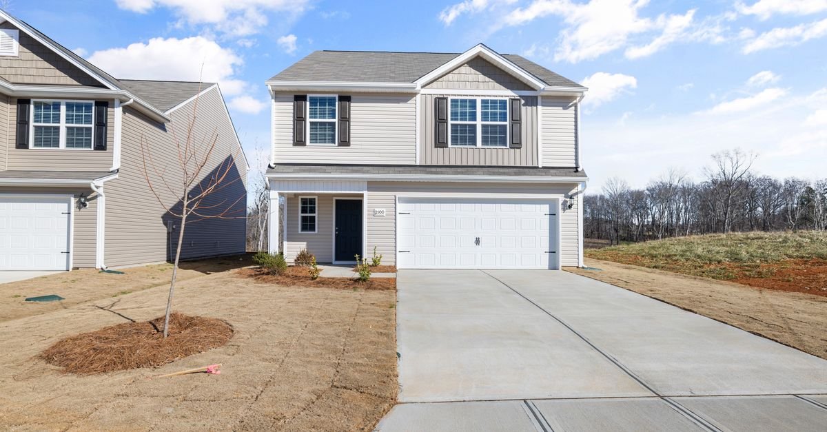 A suburban two-storey house with a wide concrete driveway leading to a double garage