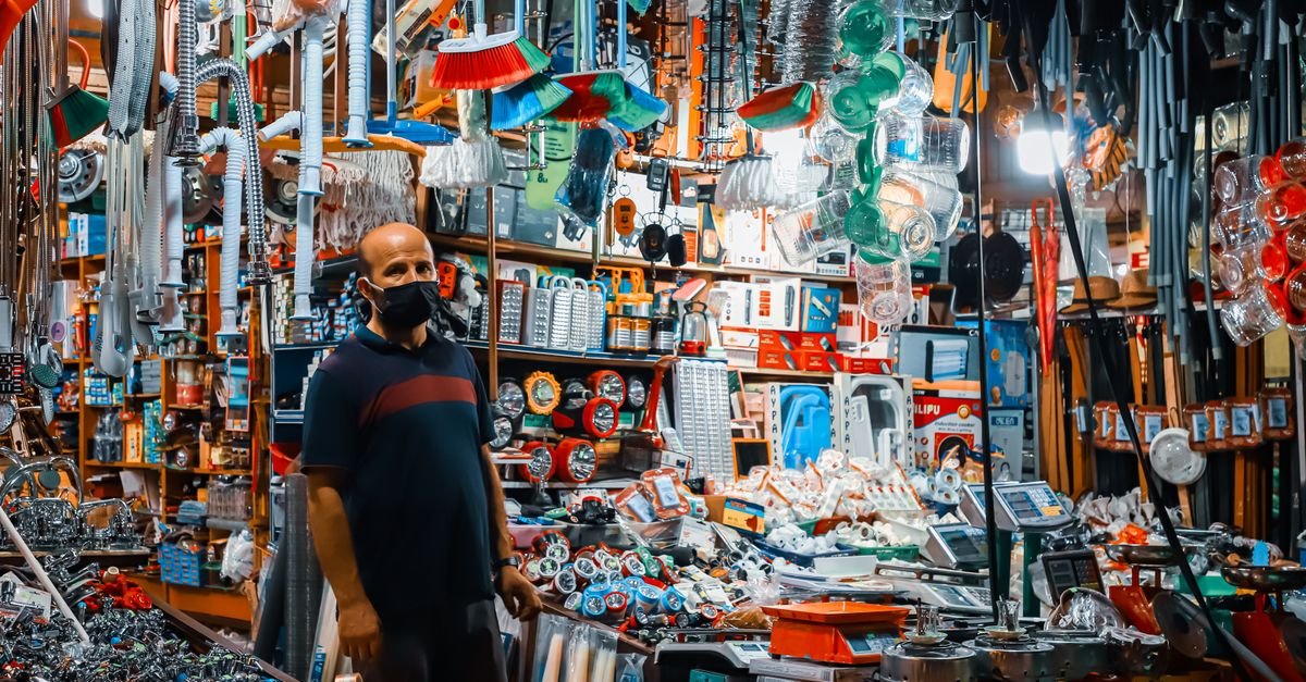 A customer browsing the aisles of a busy hardware store stocked with tools