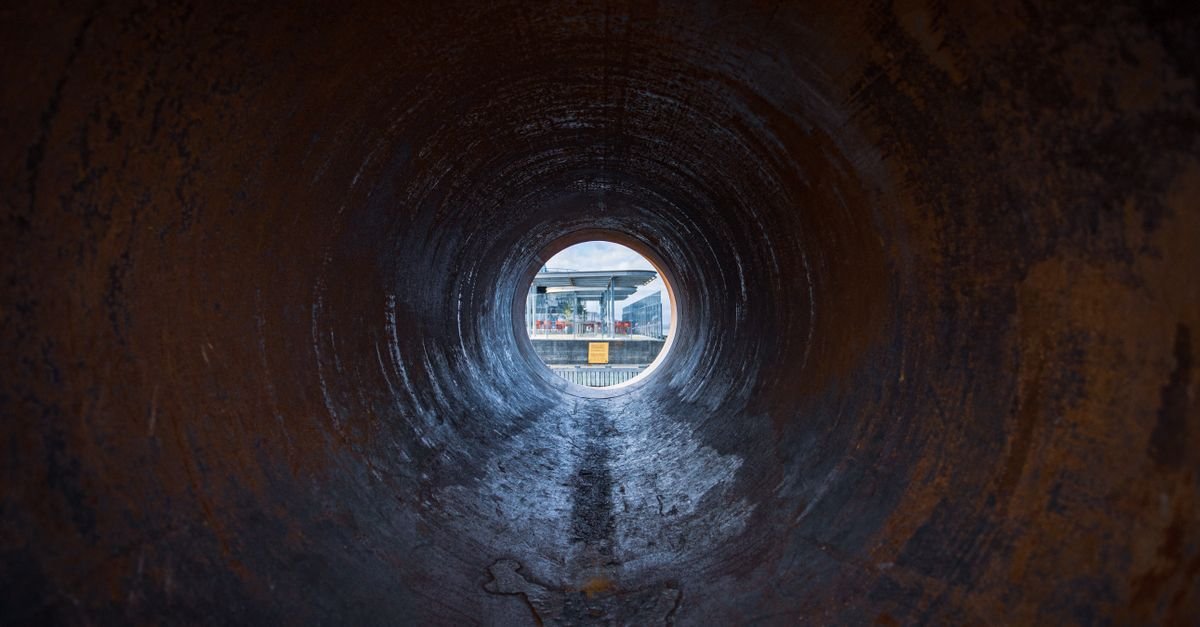 Looking down the inside of a rusted pipe to the daylight at the far end